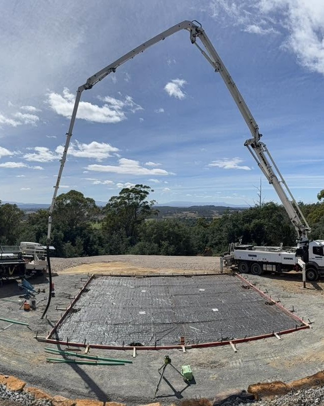 A TLM Concrete Solutions boom pump placing a rural house slab in north-west Tasmania