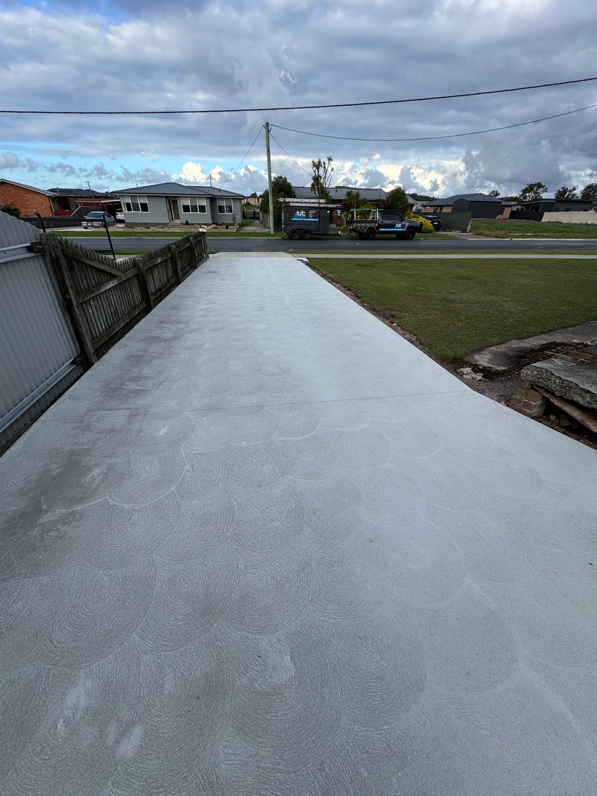 A finished concrete driveway out to the street with the TLM ute and trailer parked opposite