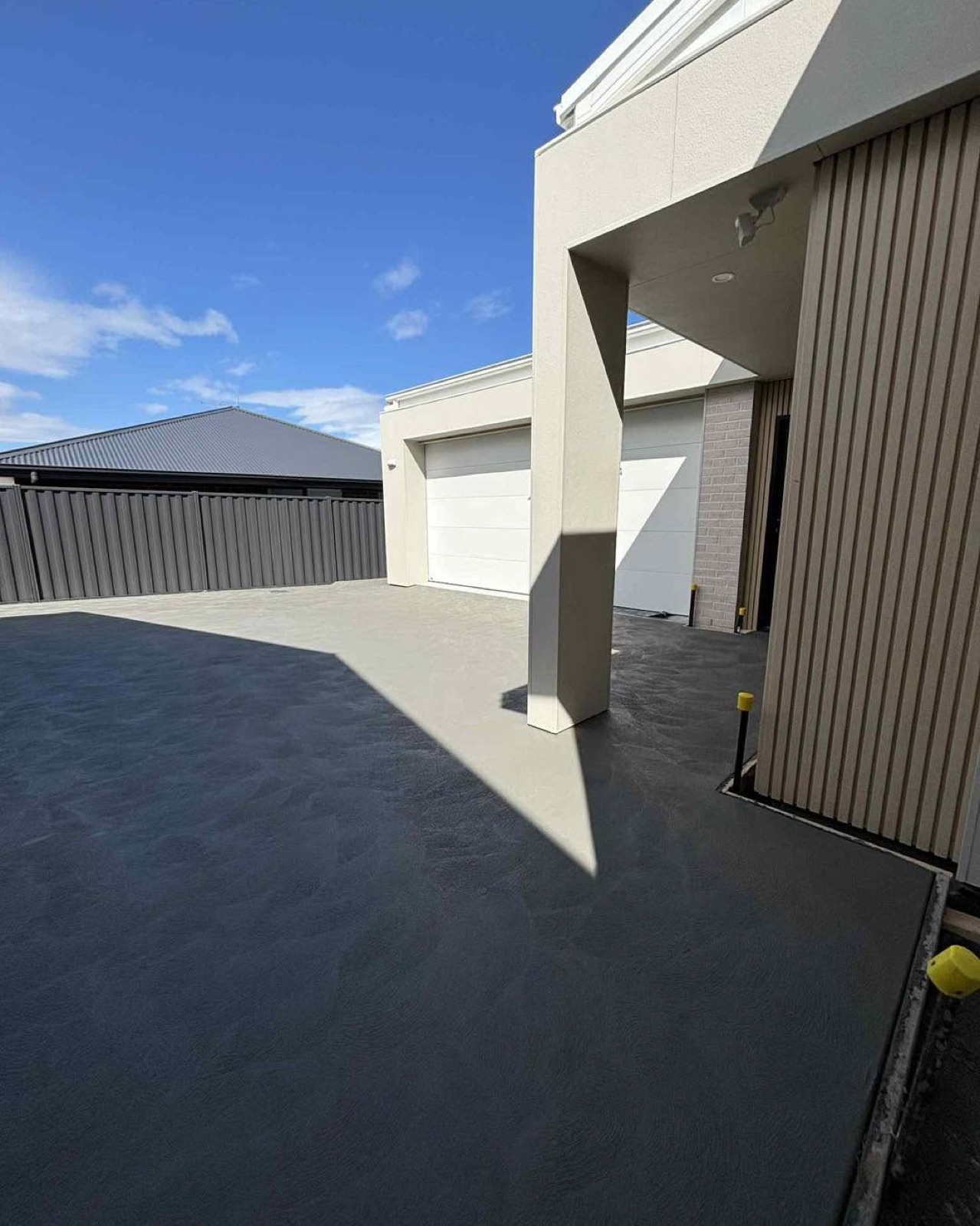 A charcoal-toned concrete courtyard in front of a double garage