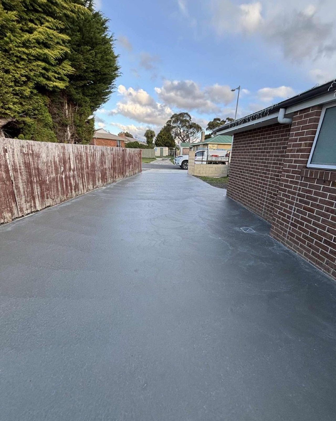 A broom-finished grey driveway beside a brick home