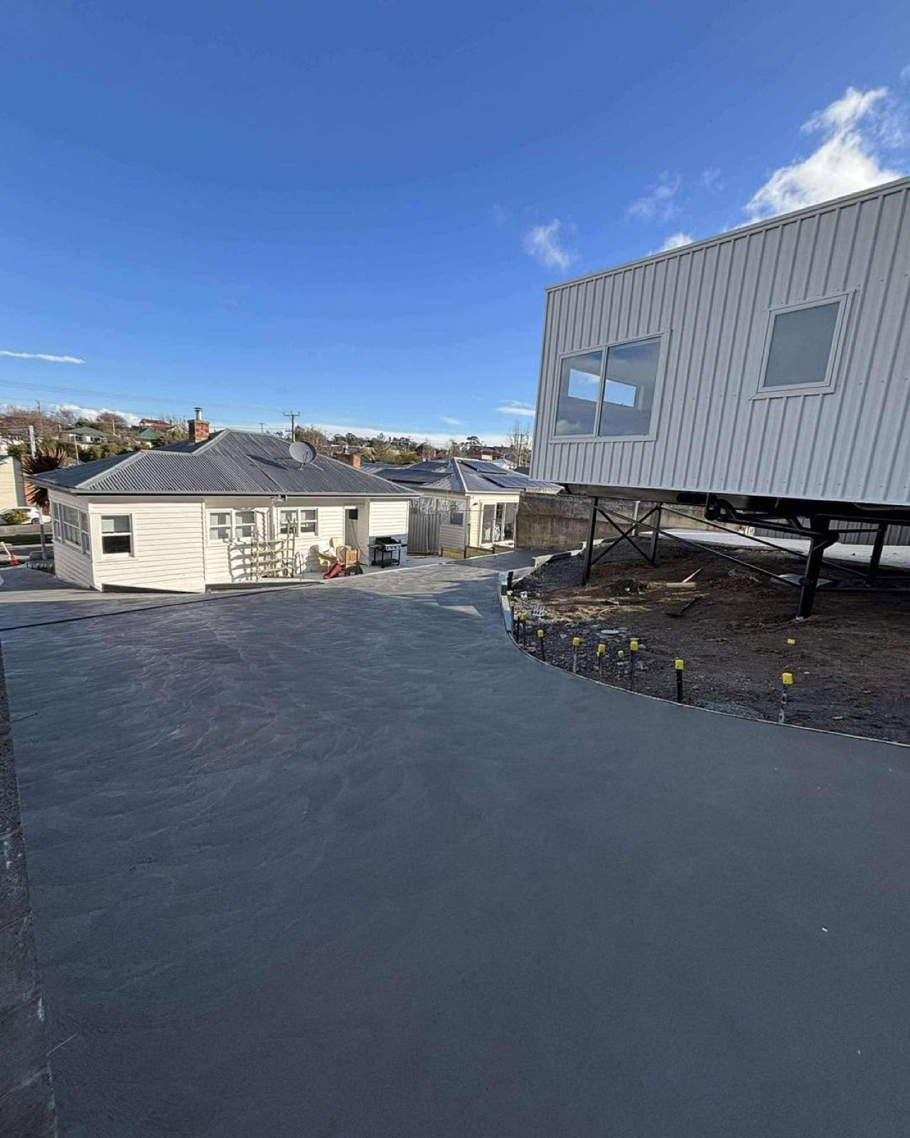 A wide charcoal concrete driveway on a residential block