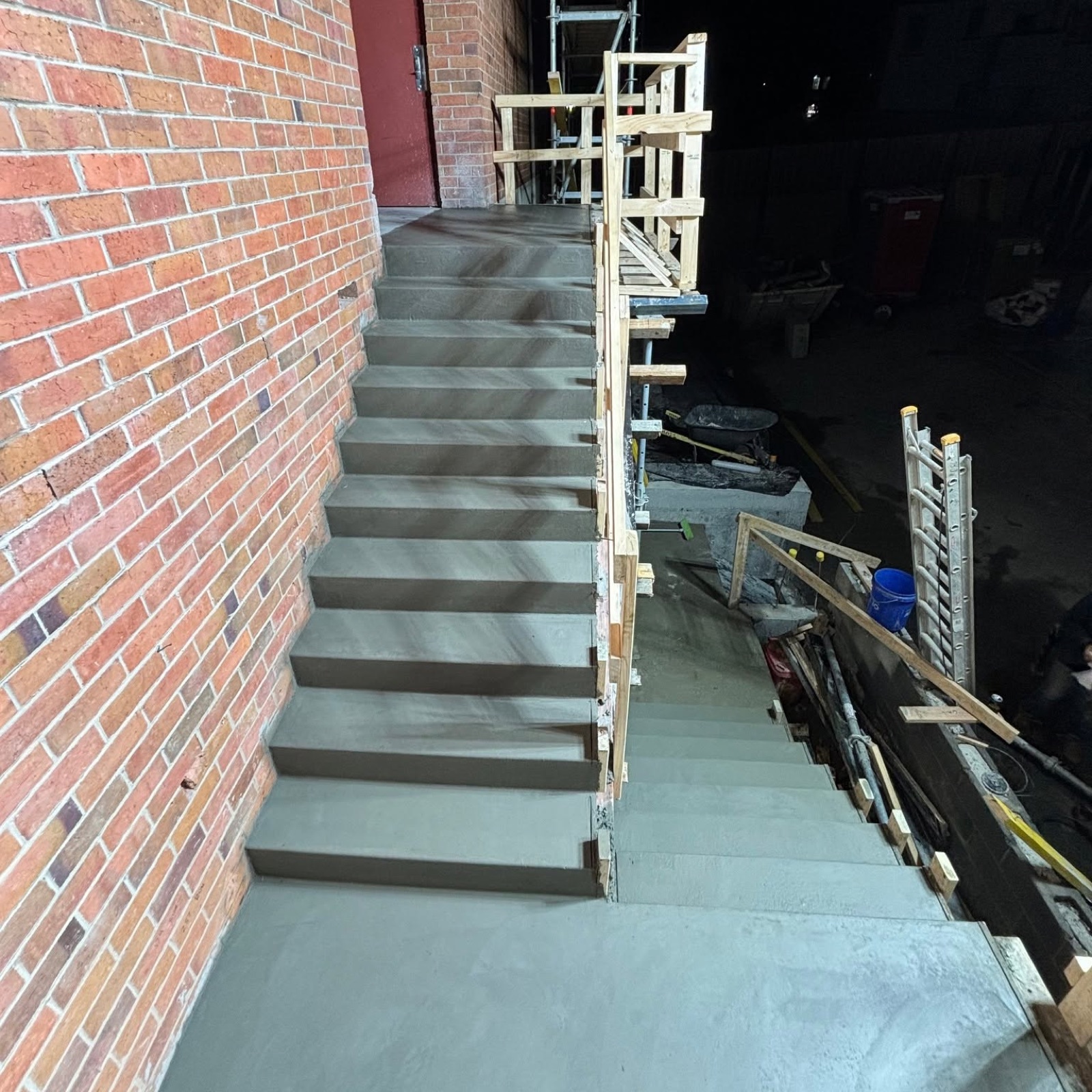 Formed concrete stairs finished against a brick wall on site